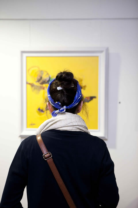 A guest looks at one of Emad Altaay's paintings**at the Freespace Gallery